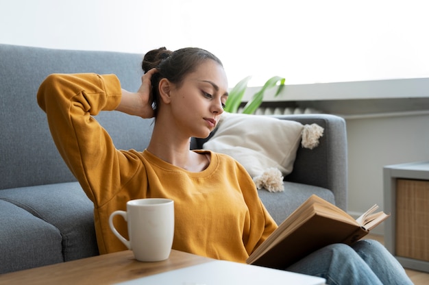 Free photo side view woman with messy bun reading