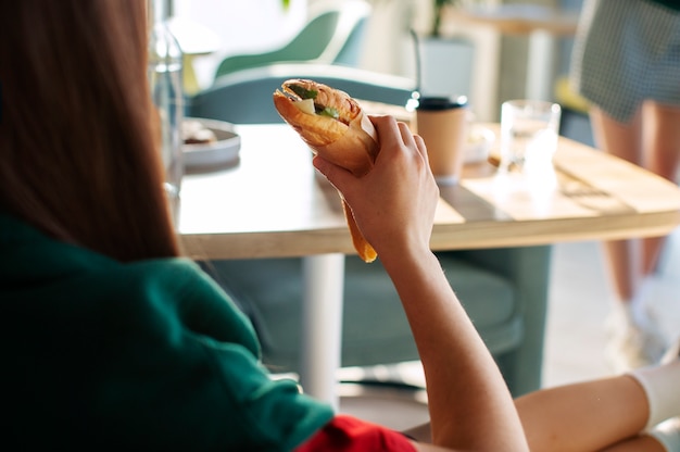 무료 사진 종이에 싸인 샌드위치 를 들고 있는 여자