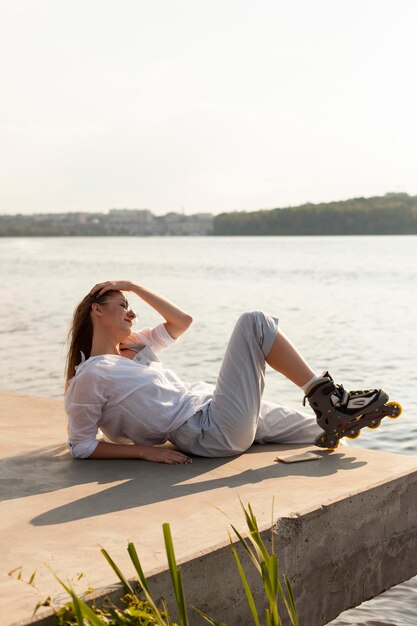 Вид сбоку женщины с роликами, любуясь видом на озеро