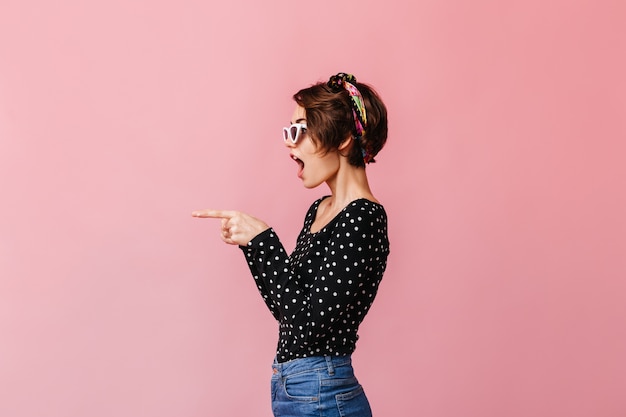 Vista laterale della donna con i capelli corti che punta con il dito