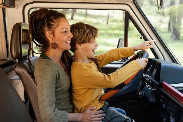 Free photo side view woman with son in her lap driving