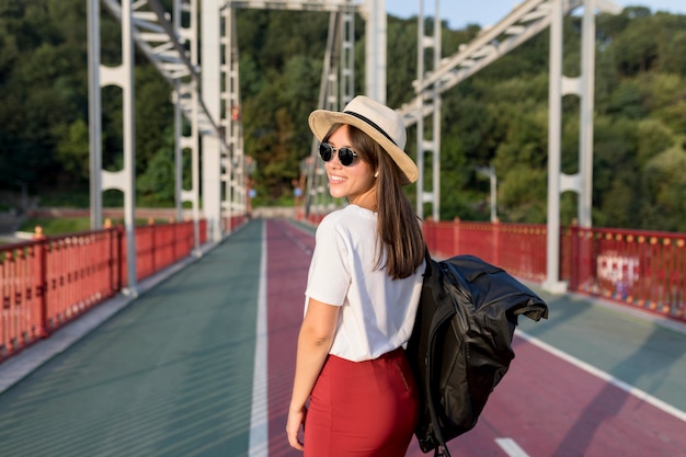 Side view of woman with sunglasses and hat posing while traveling alone