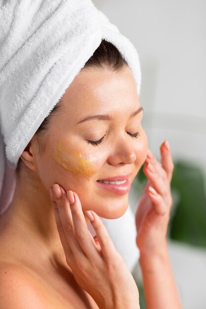 Side view of woman with towel on head applying skincare