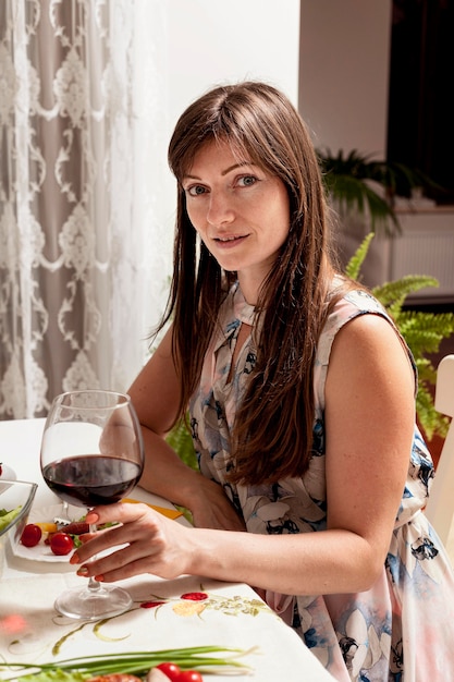 Free photo side view of woman with wine at dinner table