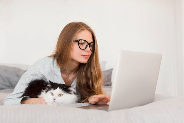 Side view of woman working on laptop from home in pajamas with cat