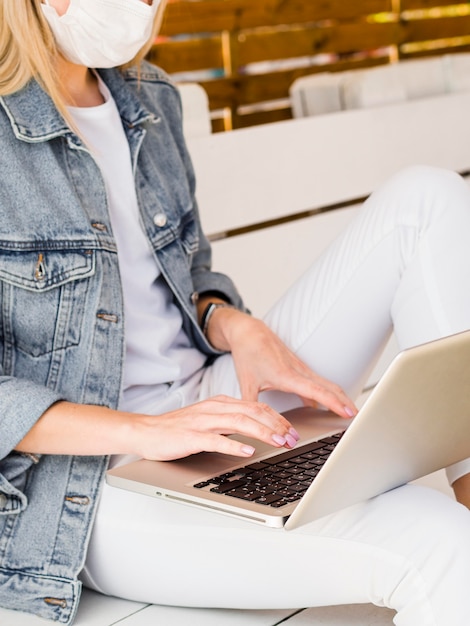 Side view of woman working on laptop while wearing face mask