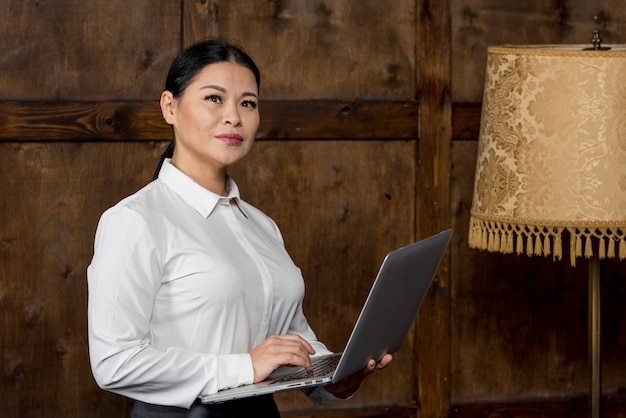 Foto gratuita donna di vista laterale che lavora al computer portatile