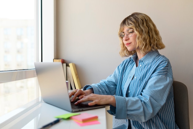 Foto gratuita donna di vista laterale che lavora al computer portatile