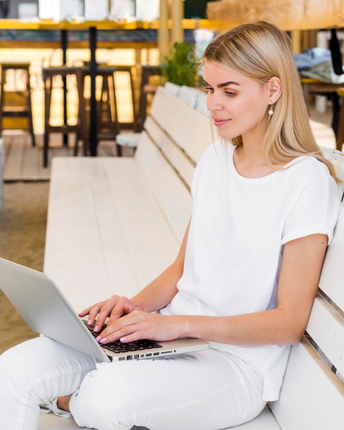 Free photo side view of woman working outside on laptop