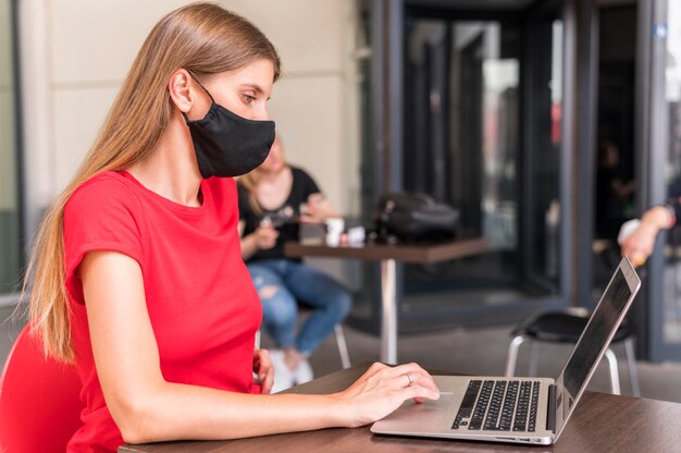 Side view woman working and wearing face mask