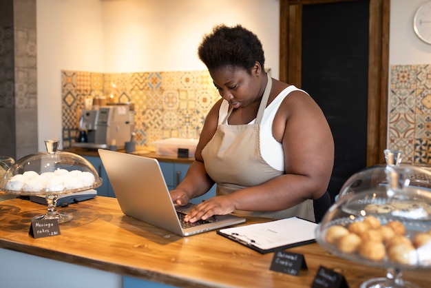 Foto gratuita donna di vista laterale che lavora con il computer portatile