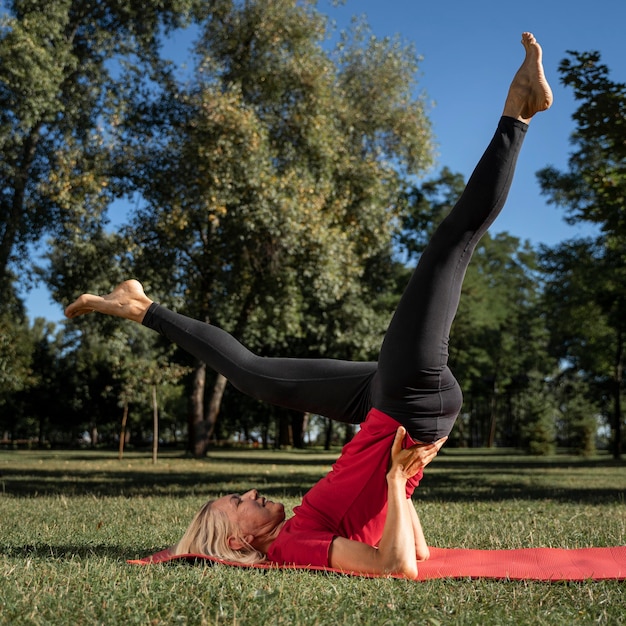 Вид сбоку женщины в позе йоги на открытом воздухе