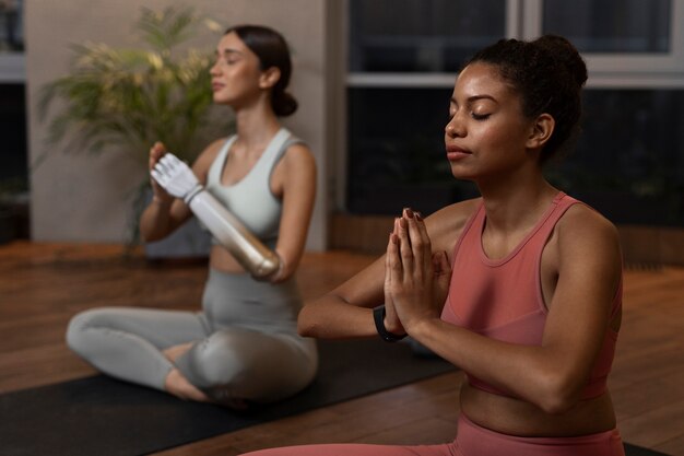 Side view women doing yoga together