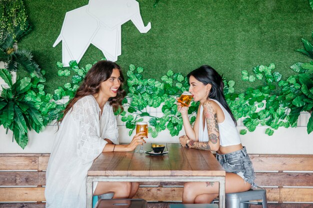 Side view of women drinking beer at table