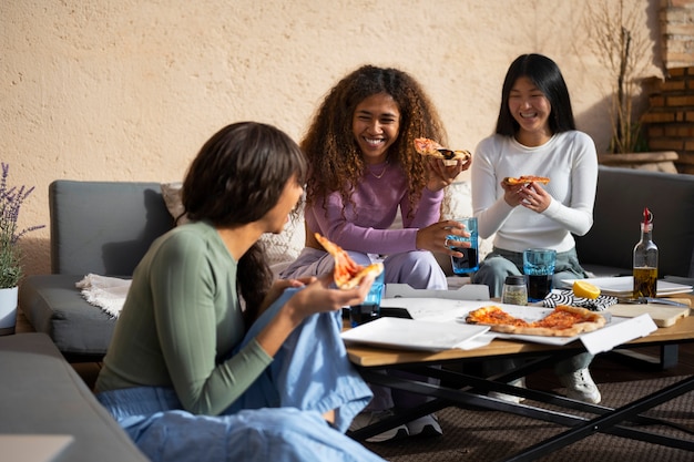 Free photo side view women eating delicious pizza