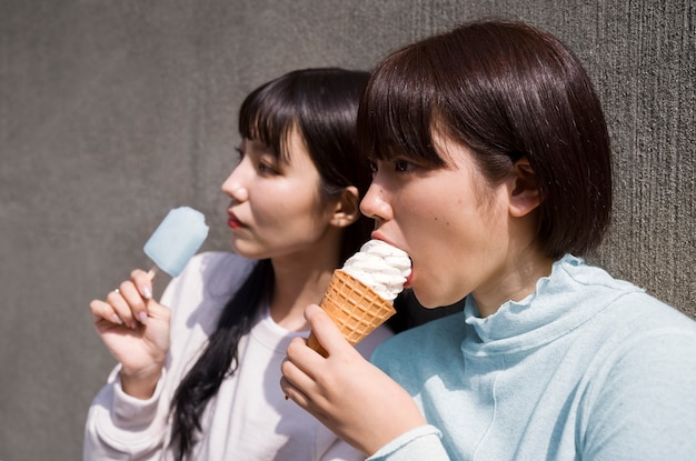 Free photo side view women eating ice cream together