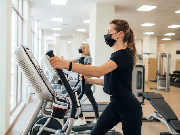 Free photo side view of women exercising at the gym during pandemic