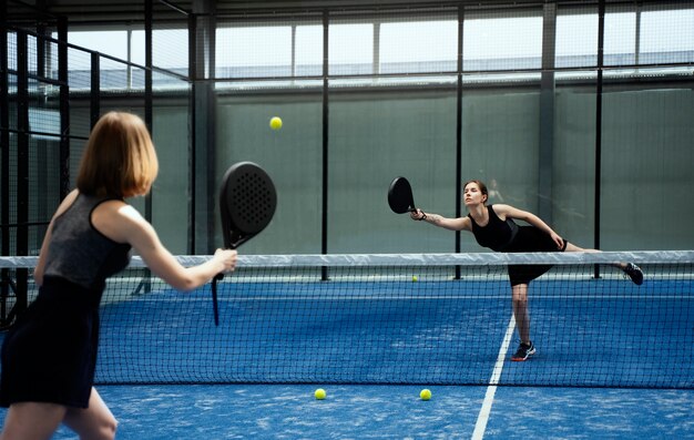 Side view women playing paddle tennis