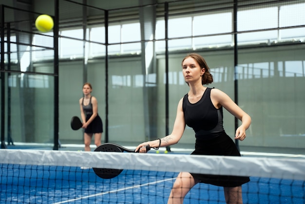 Side view women playing paddle tennis