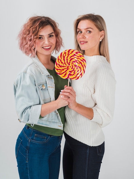 Free photo side view of women posing with lollipop for valentines