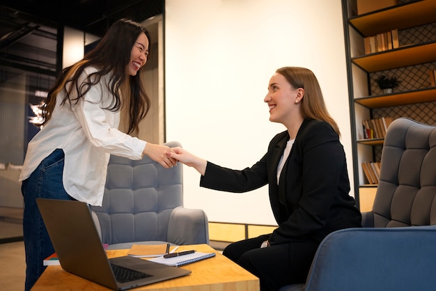 Free photo side view women shaking hands