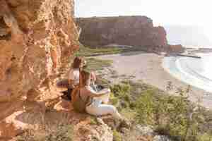 Free photo side view women sitting on a coast with copy space