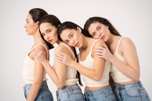 Free photo side view of women in tank tops and jeans posing in minimalist portraits