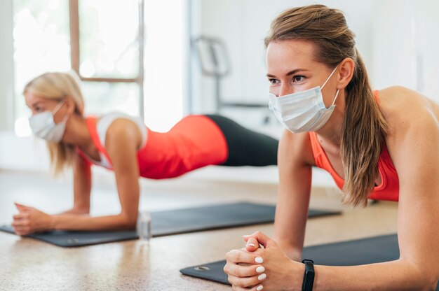 Side view of women with medical masks working out together