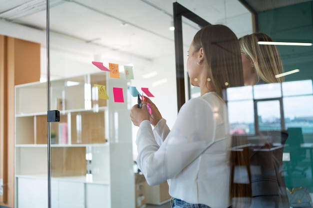 Free photo side view women working with post-its