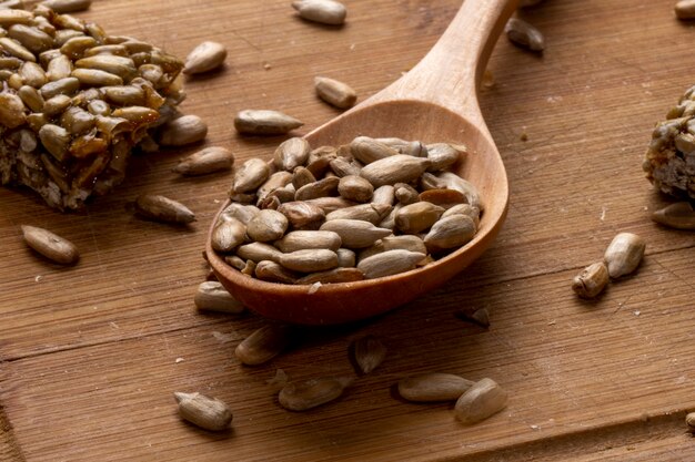 Side view of a wooden spoon full of sunflower seeds with sweet kozinaki on wooden