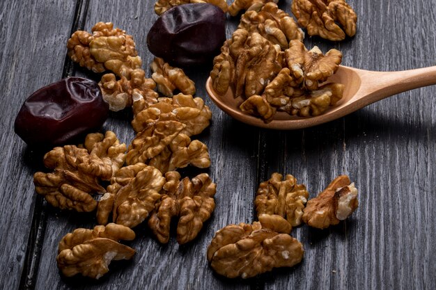 Side view of a wooden spoon with walnuts and sweet dried date fruits on rustic