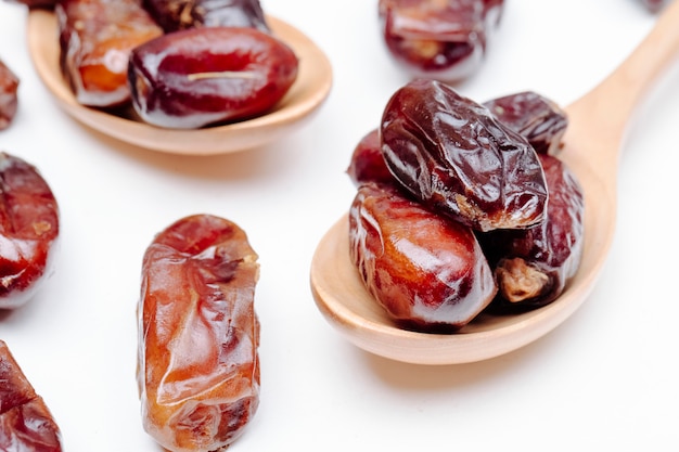 Side view of wooden spoons with dried dates on white background