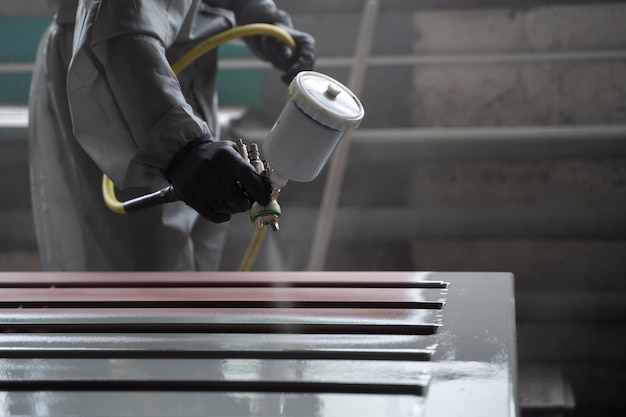 Free photo side view worker spraying powder paint from a gun