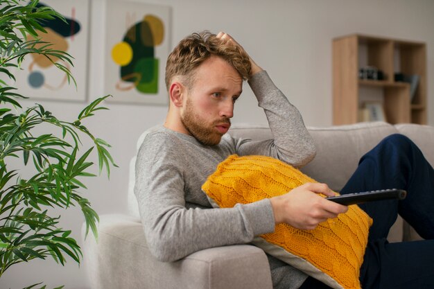 Side view worried man on couch watching tv