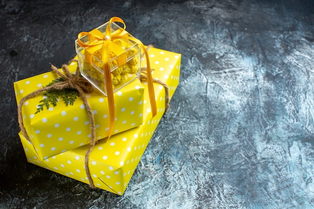 Side view of Xmas background with beautiful yellow gift boxes on the right side on dark table