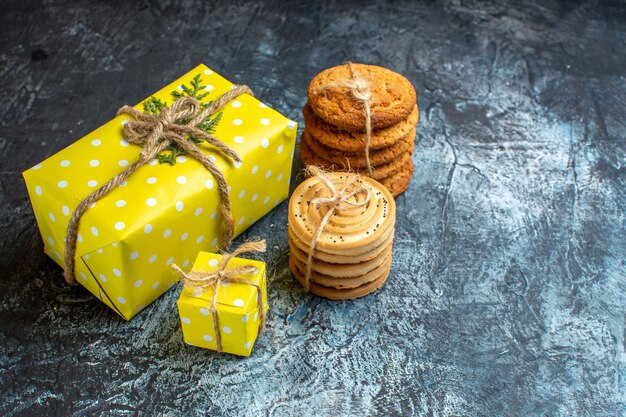 Side view of Xmas background with beautiful yellow gift boxes and stacked cookies on dark table