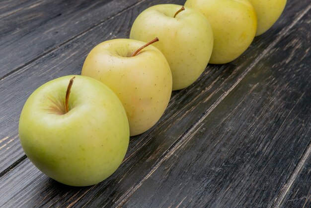 side view of yellow apples on wooden background