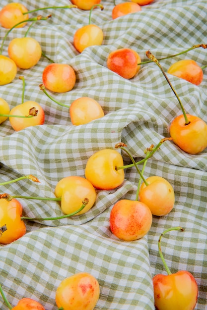 Foto gratuita vista laterale di ciliegie gialle sul panno plaid