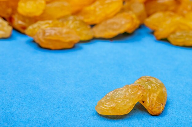 Side view of yellow dried raisins isolated on blue background