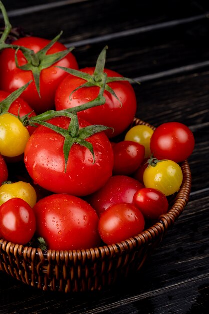 Side view of yellow and red tomatoes in basket on wood