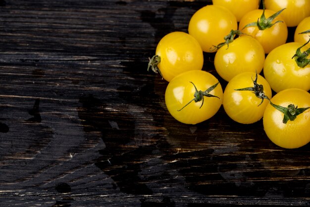 Free photo side view of yellow tomatoes on wooden surface with copy space