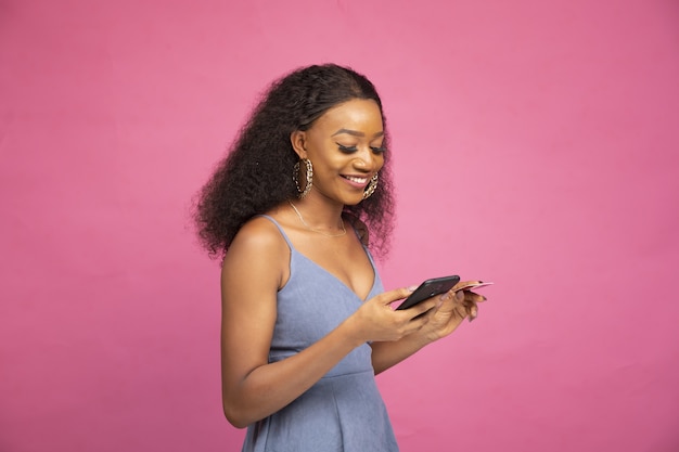 Free photo side view of a young african female shopping online using her smartphone and credit card