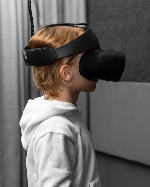 Free photo side view of young boy using virtual reality headset