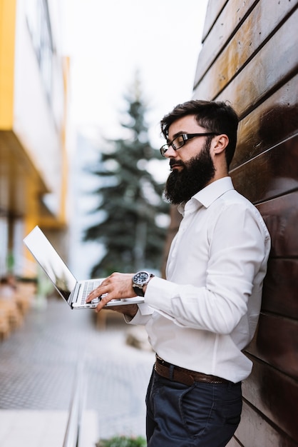 Foto gratuita vista laterale di giovane uomo d'affari che utilizza computer portatile all'aperto