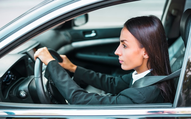 Side view of a young businesswoman driving car