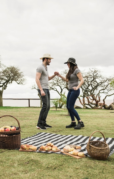 Side view of young couple dancing together at picnic in the park