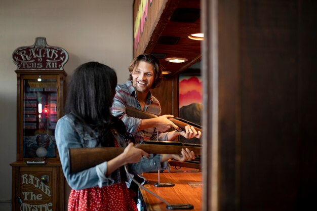 Side view of young couple playing target shooting game while on a date