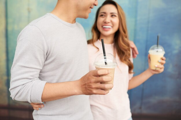 Side view of young couple taking a romantic walk on a date with milkshakes