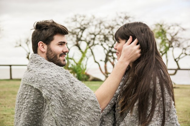 Side view of young couple wrapped in the blanket