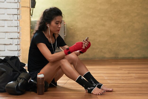 Side view of young female athlete listening to music after the workout
